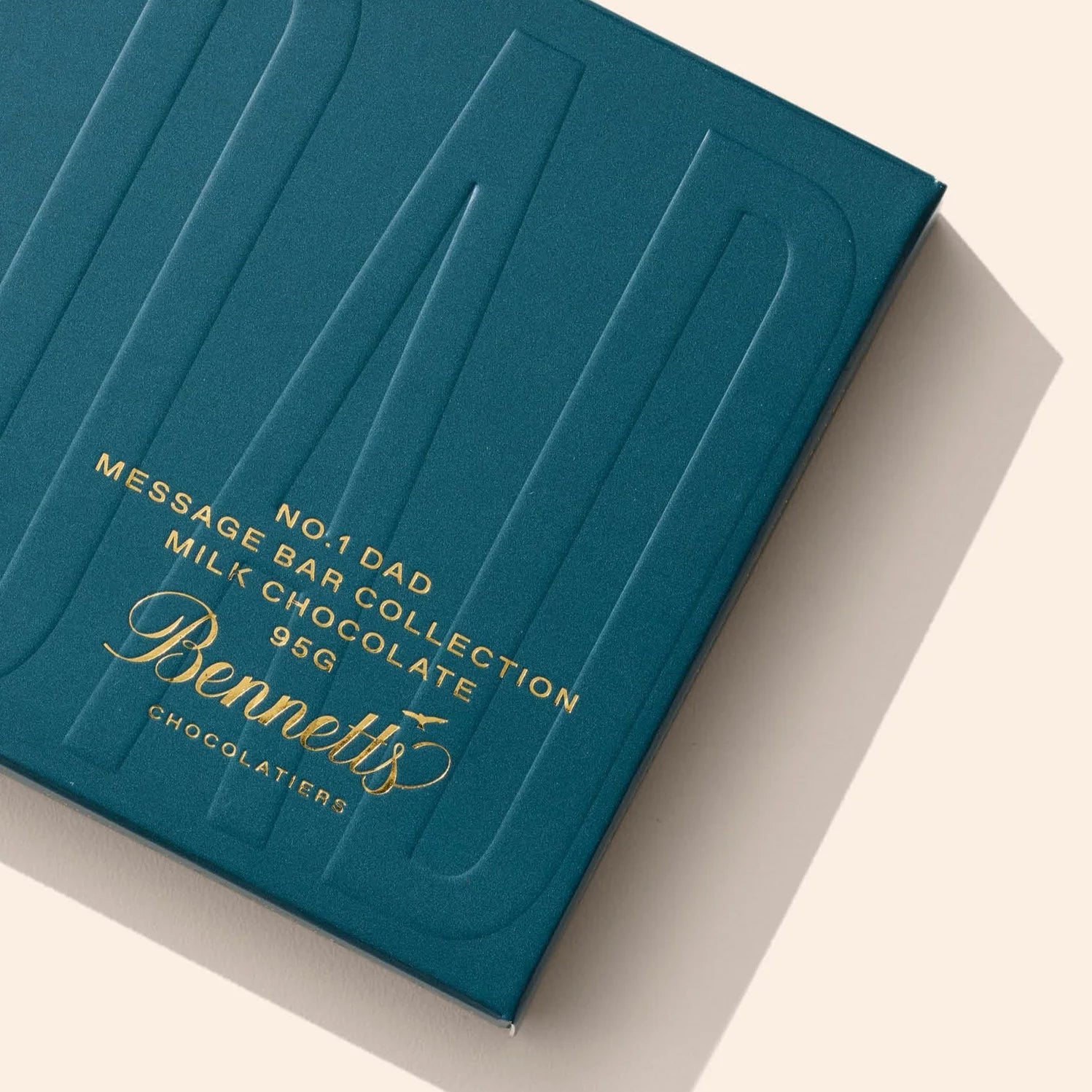 Blue chocolate bar packaging with gold text on a beige background