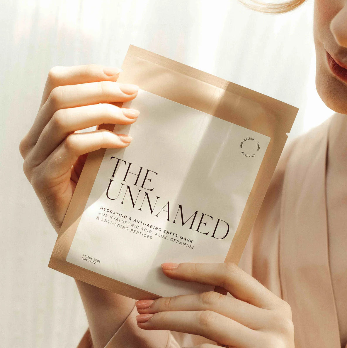 Person holding a 'The Unnamed' face mask package against a neutral background