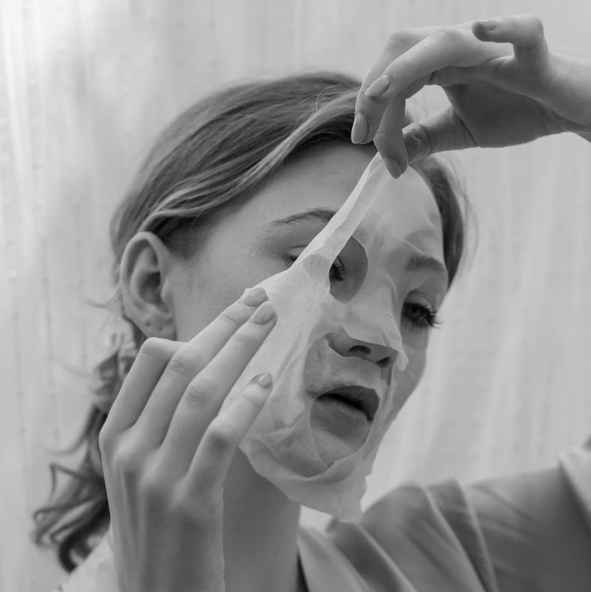 Person applying a face mask in a bathroom setting