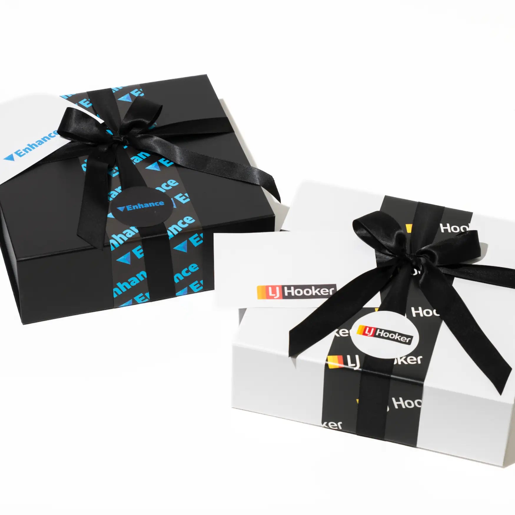 Black and white gift boxes adorned with black satin ribbons and branded stickers.