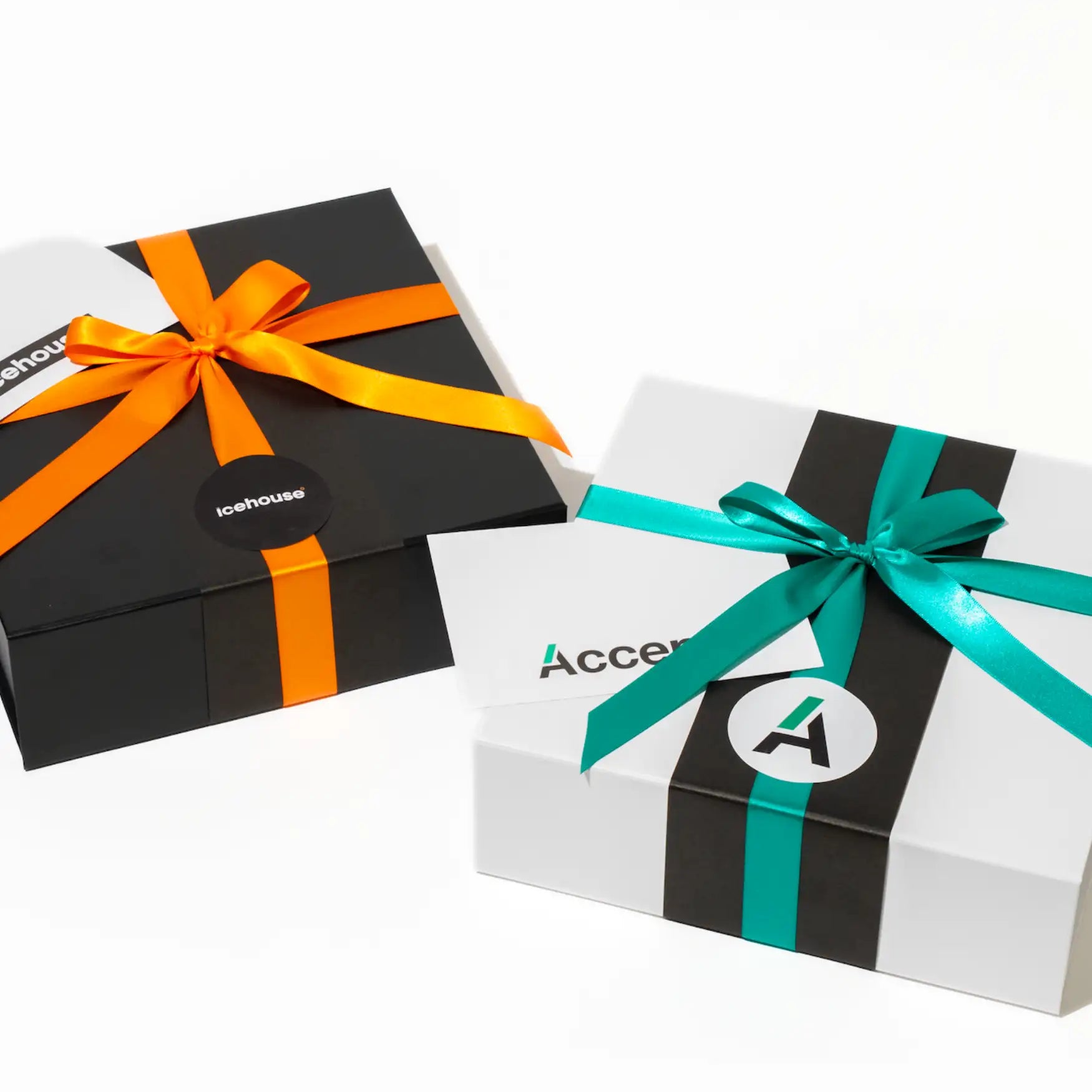 Black and white gift boxes adorned with vibrant orange and teal satin ribbons, each featuring branded stickers.