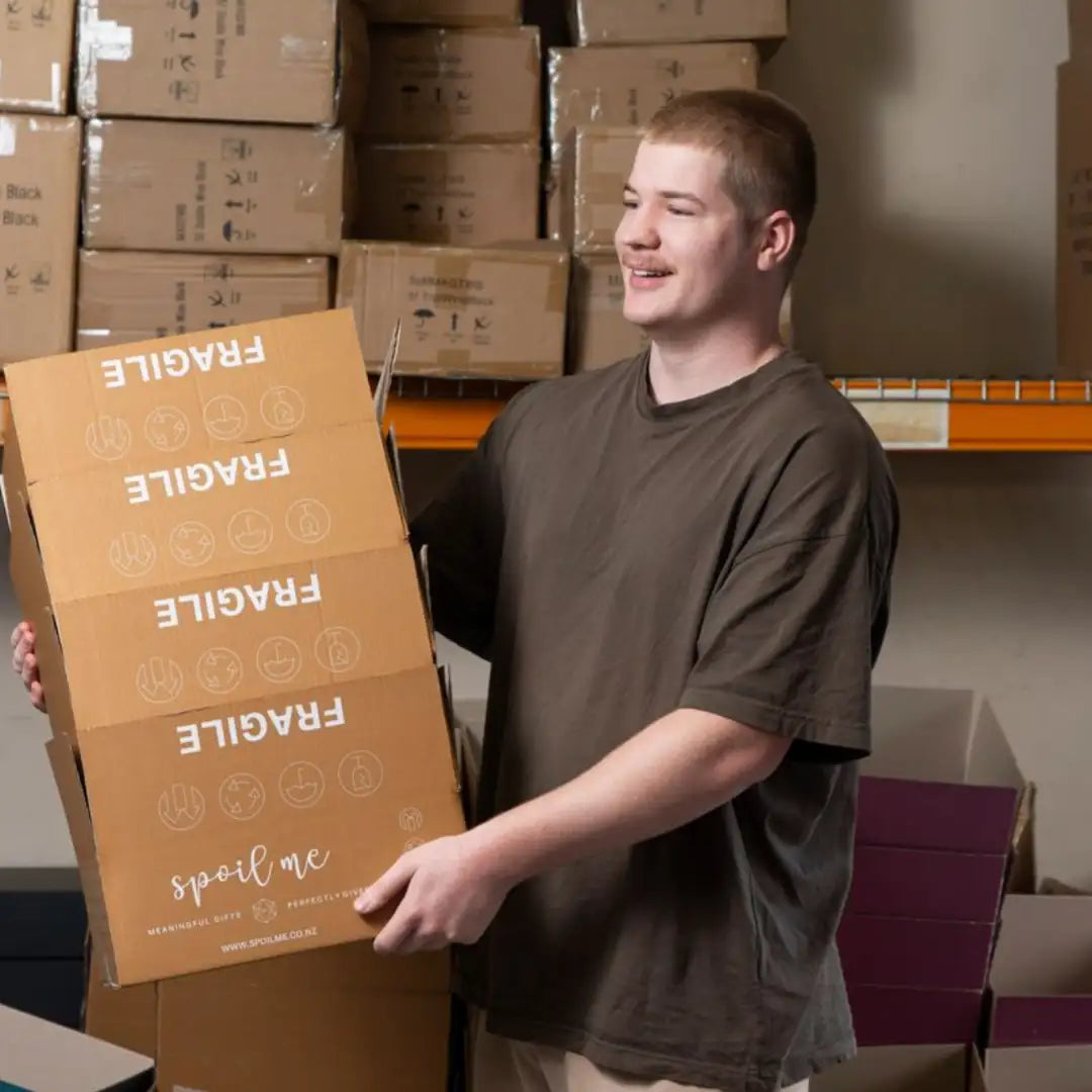 Brown cardboard box with ’fragile’ printed in white and the phrase ’spoil me’ at the bottom